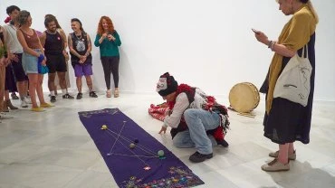 Pablucha dibuja las líneas de los caminos del agua andino y cuenta la historia de Chuquisuso, la mujer que vence la sequía, en la actividad Rimanakuy, entre el romero y la coca. Taller sobre idiomas amerindios, Museo Reina Sofía, 2024. Fotografía: Carla Rosario Amaro Carreño