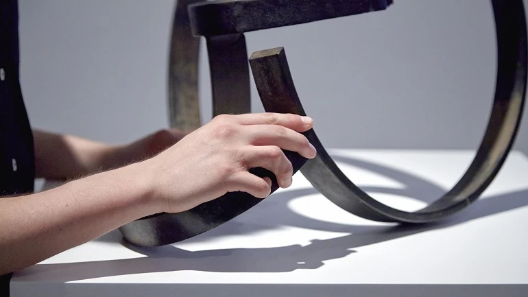Persona ciega explorando una escultura de Jorge Oteiza