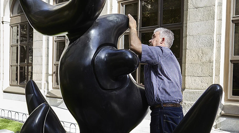 Persona ciega explorando una escultura de Joan Miró en el jardín de Sabatini.