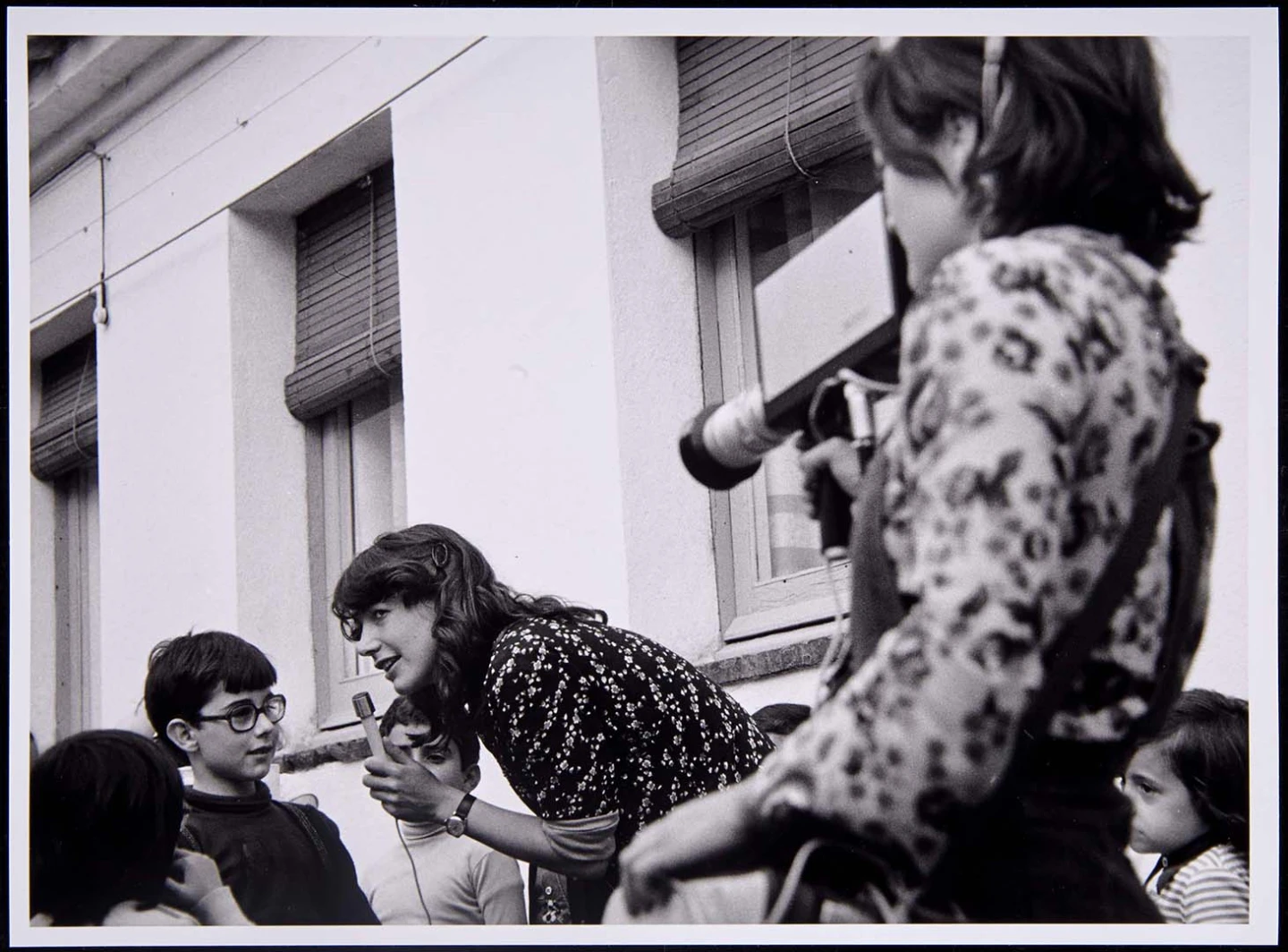 Fotografía de Video-Nou en la campaña de la Lliga de Catalunya por los pueblos de Girona. Lluïsa Ortínez filma y Mª Lluïsa Roca entrevista a un grupo de niños, Girona, 1977. Fondo Video-Nou. Biblioteca y Centro de Documentación del Museo Reina Sofía