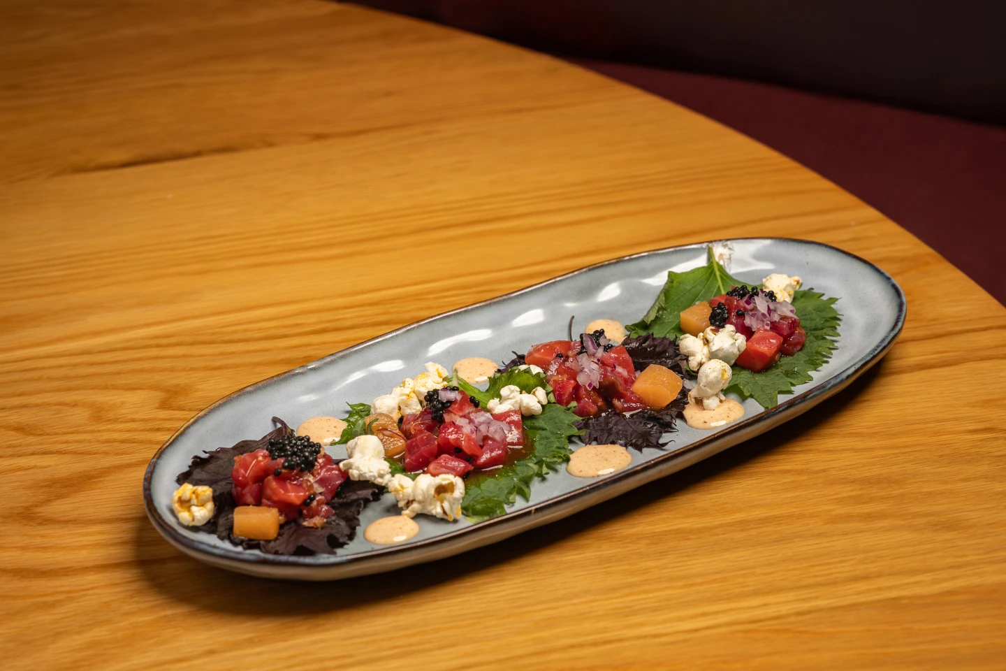 Tartar de salmón con kimchi y palomitas sobre hojas de Shiso