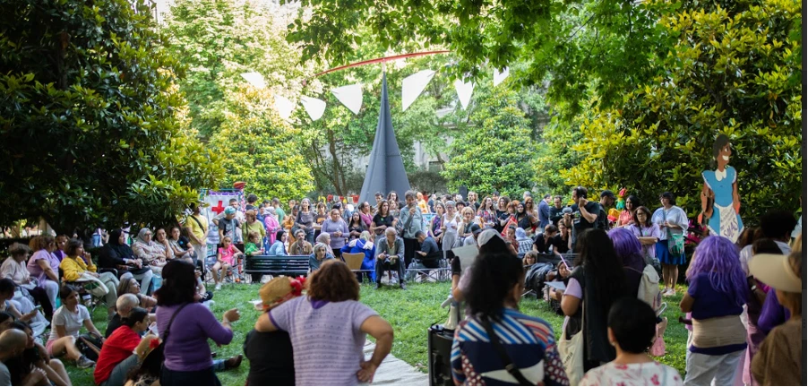 La imagen muestra una multitud durante el Picnic del Barrio en el Jardín del Museo Reina Sofía. Algunas personas están disfrazadas.
