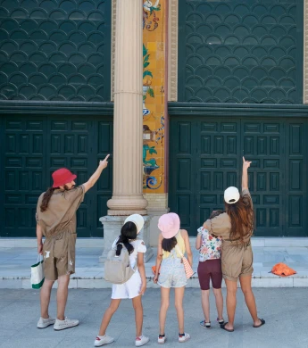 Una familia frente a las puertas del Palacio de Velázquez, señalando algo arriba
